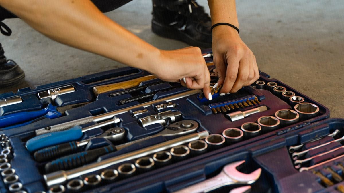 Hands carefully select the right tool from a fully packed, organized toolbox.