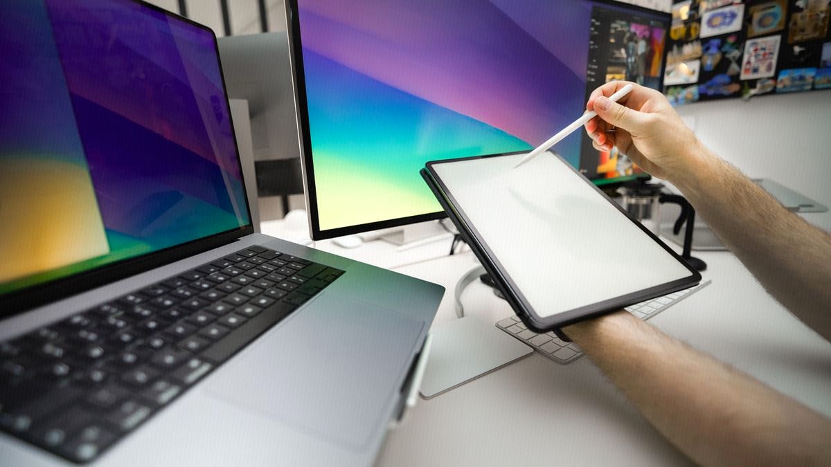 A freelancer sketches on a graphics tablet in a multi-monitor home studio setup.