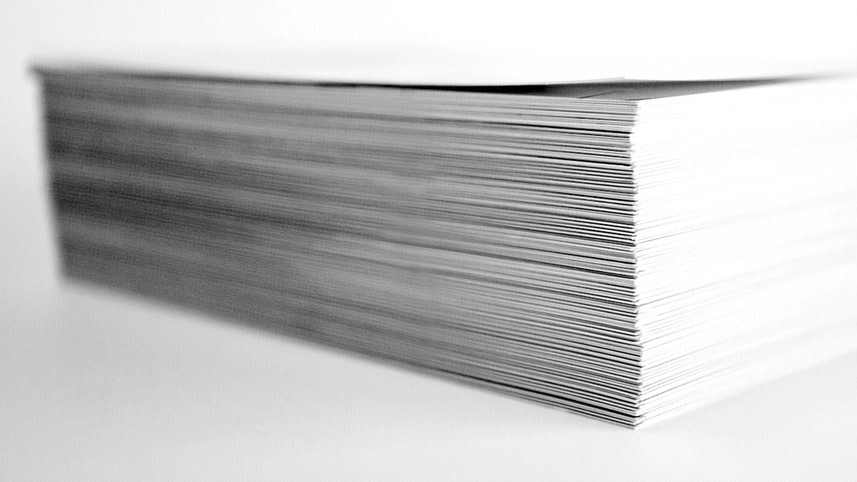 A thick stack of blank printed paper sits edge-on against a plain white background, emphasizing its height.